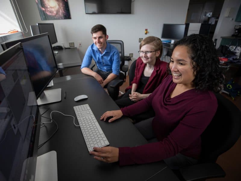 Students smiling and working together in computer lab