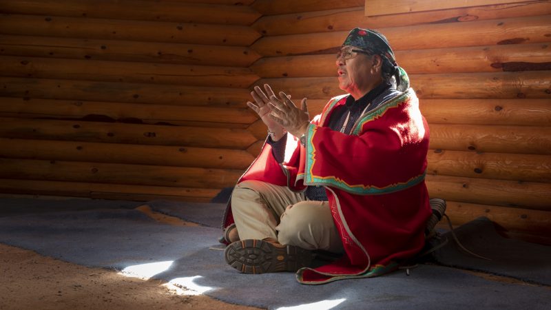 Lorenzo Max sitting on the floor in a wood house.