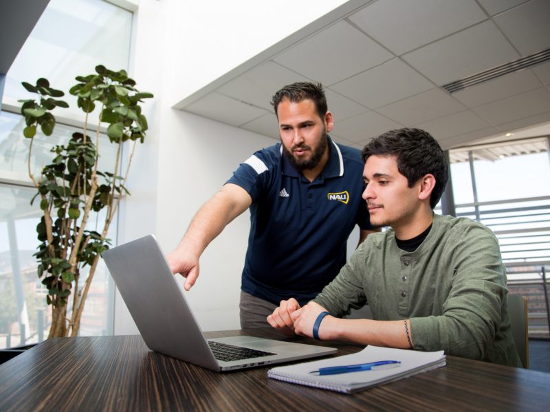 Instructor points to laptop screen student is looking at.