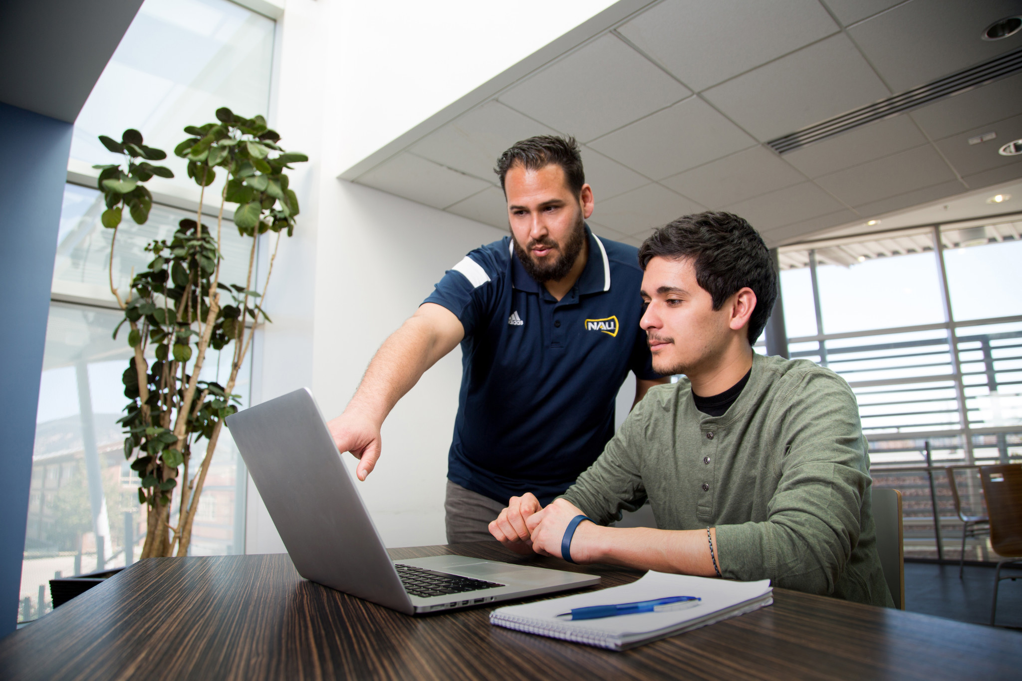 Instructor points to laptop screen student is looking at.