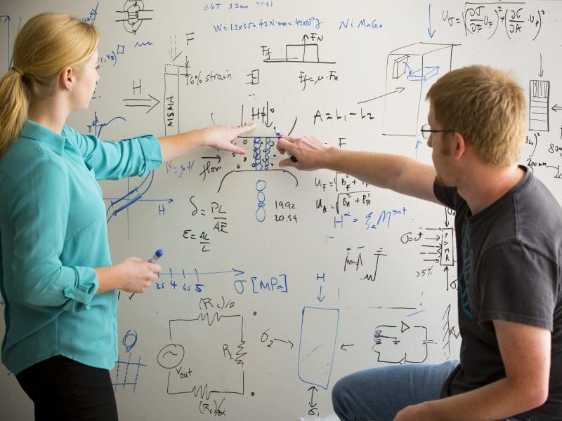 Students pointing and writing on whiteboard