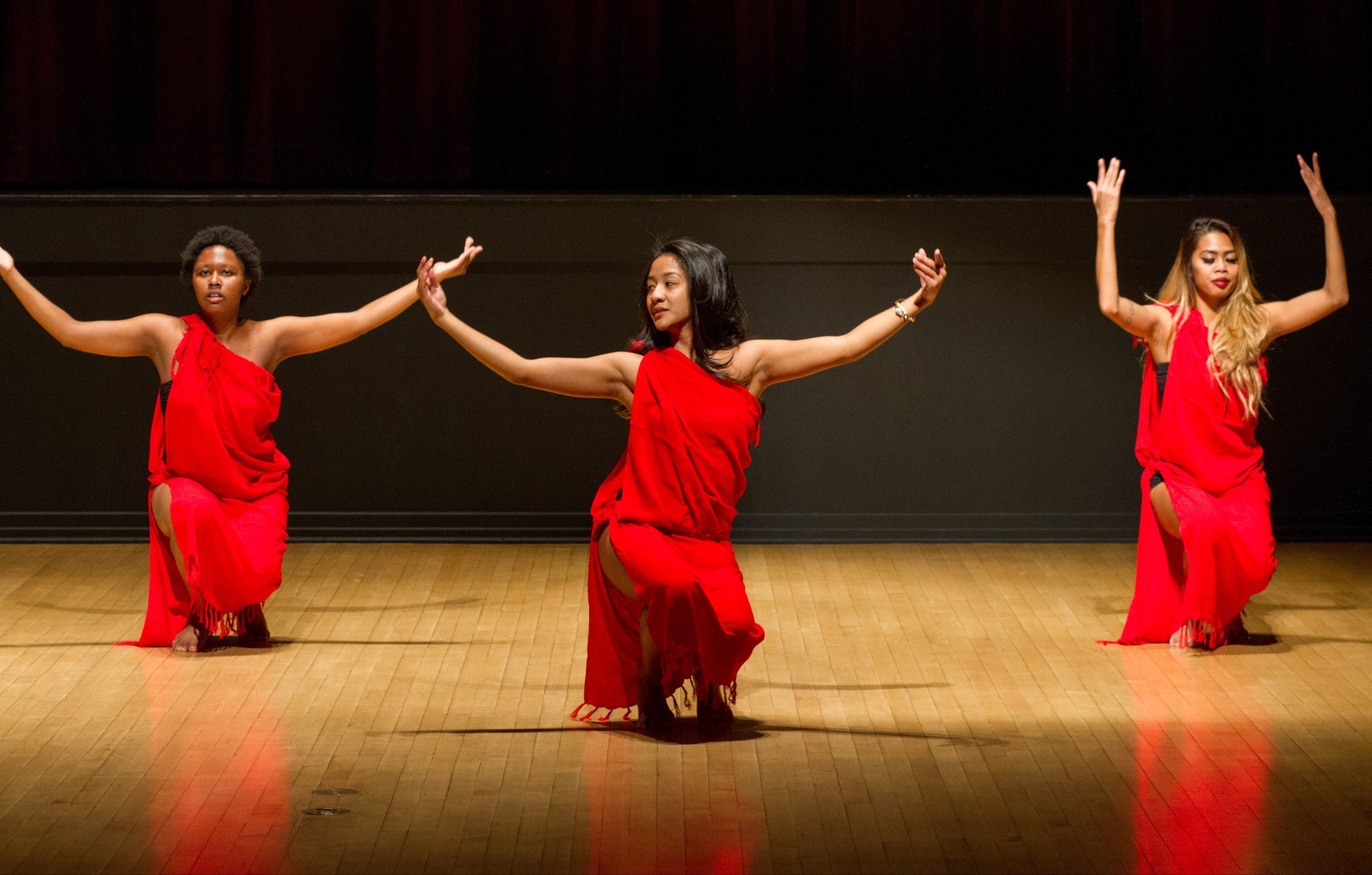 Students dancing on stage wearing dresses.