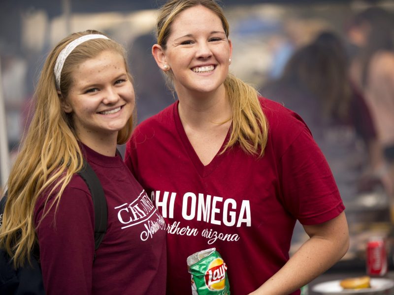Students wearing greek life shirts smile at the camera.