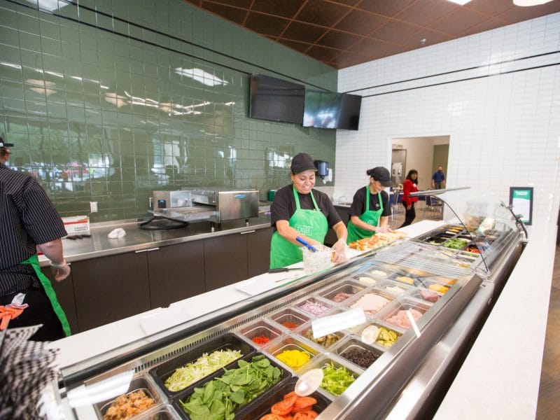 Employees prepare food in buffet dining hall.