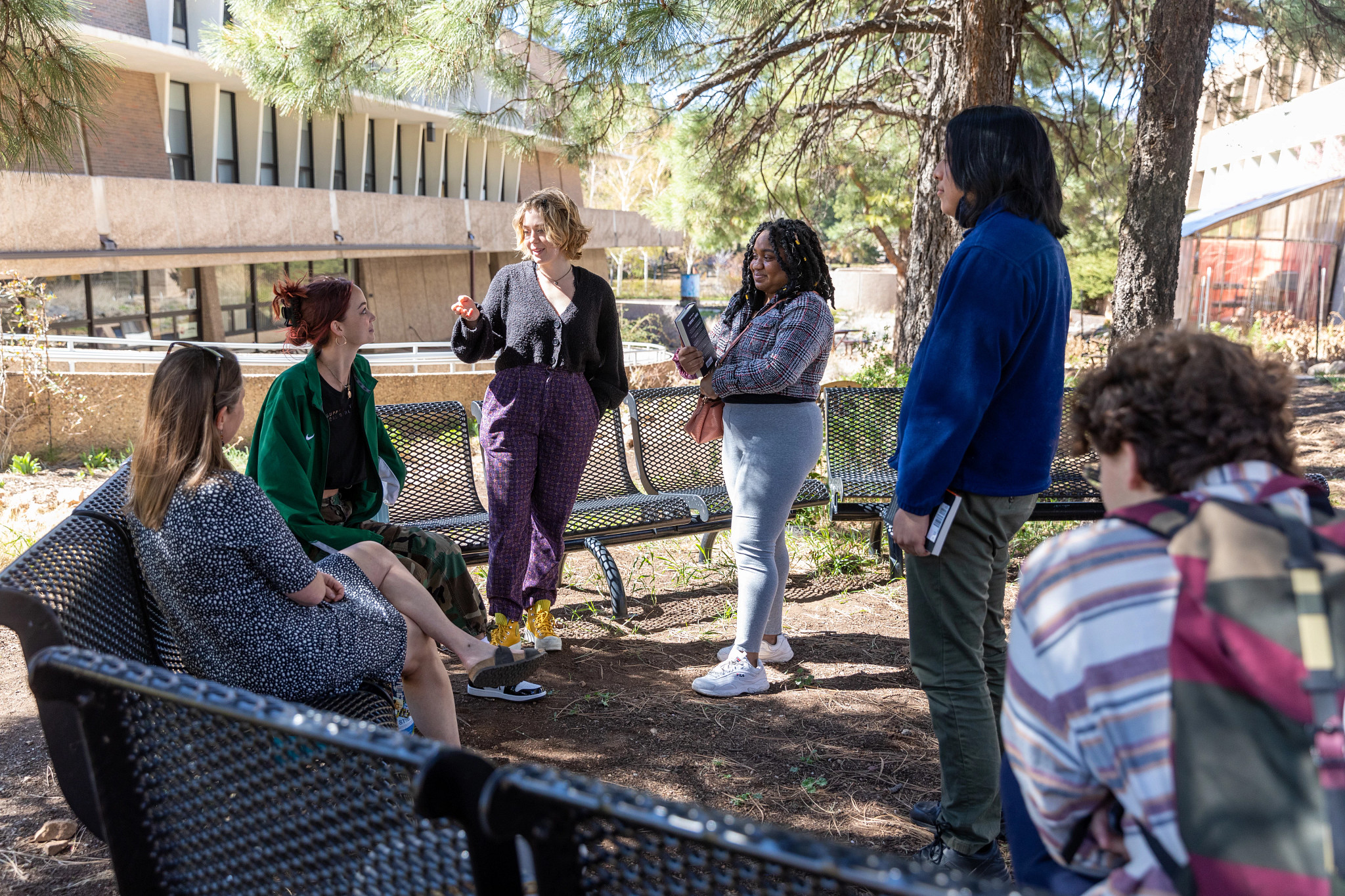 Students gather outside on benches.