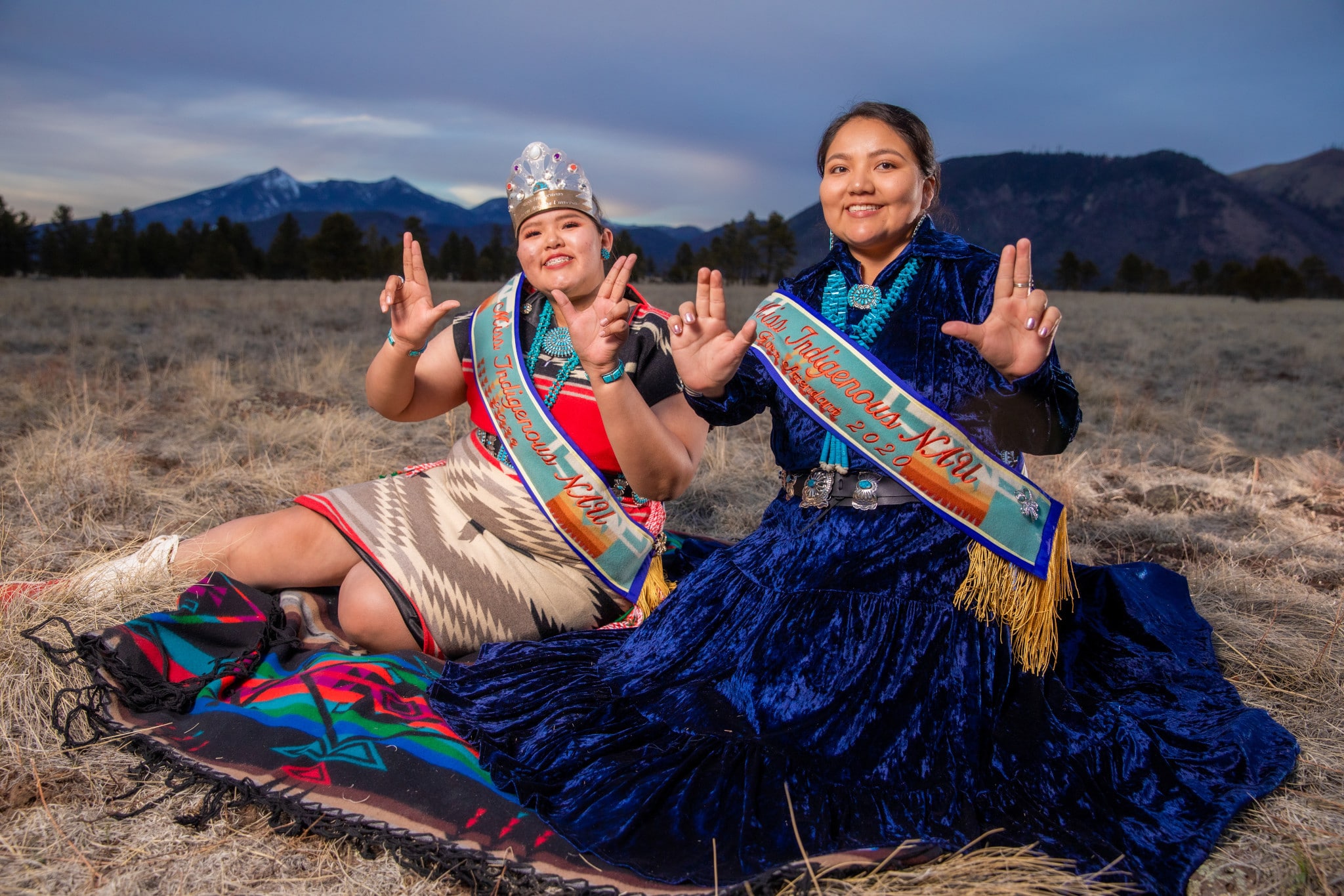 Two Native American women sitting in a field.