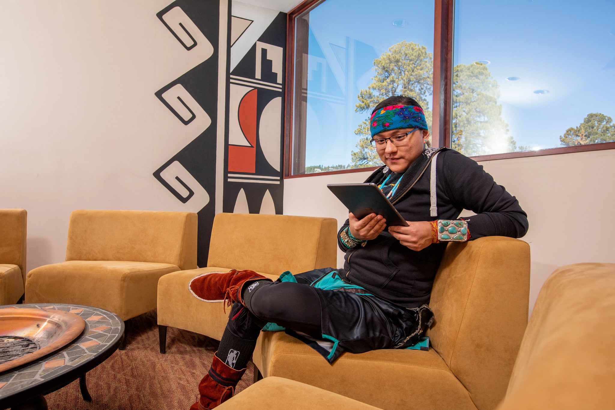 Student sits on couch and looks at tablet.