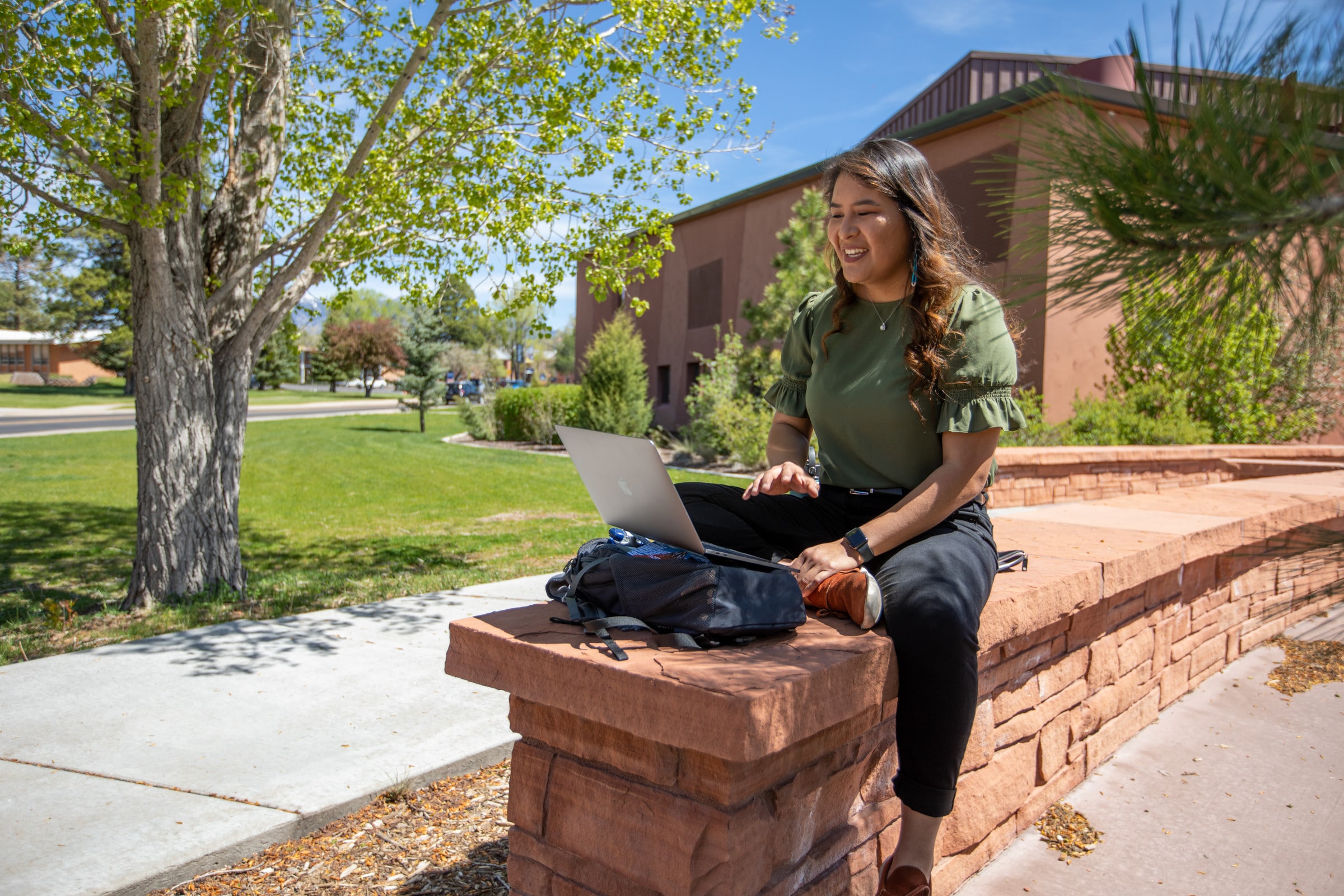 Jayne Sandoval sitting outside with her laptop.