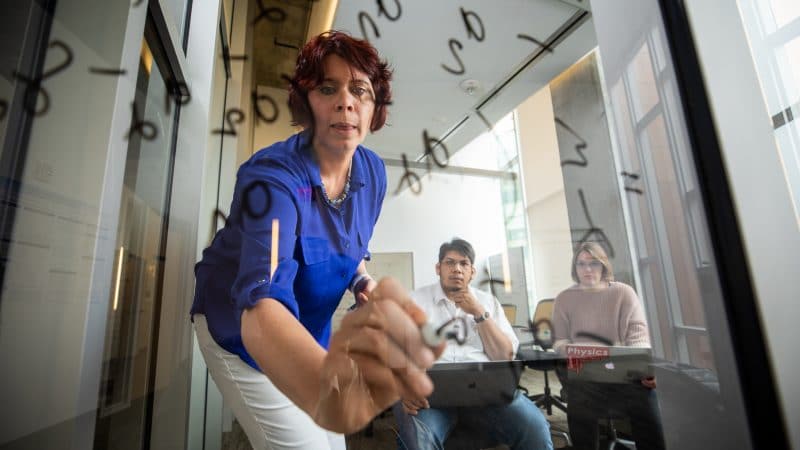 Ines Montano writing on board with students.