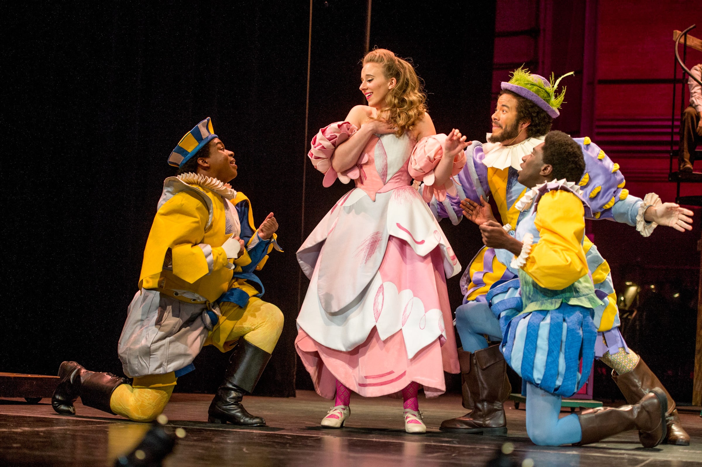 Performing arts students dance in costumes on stage.