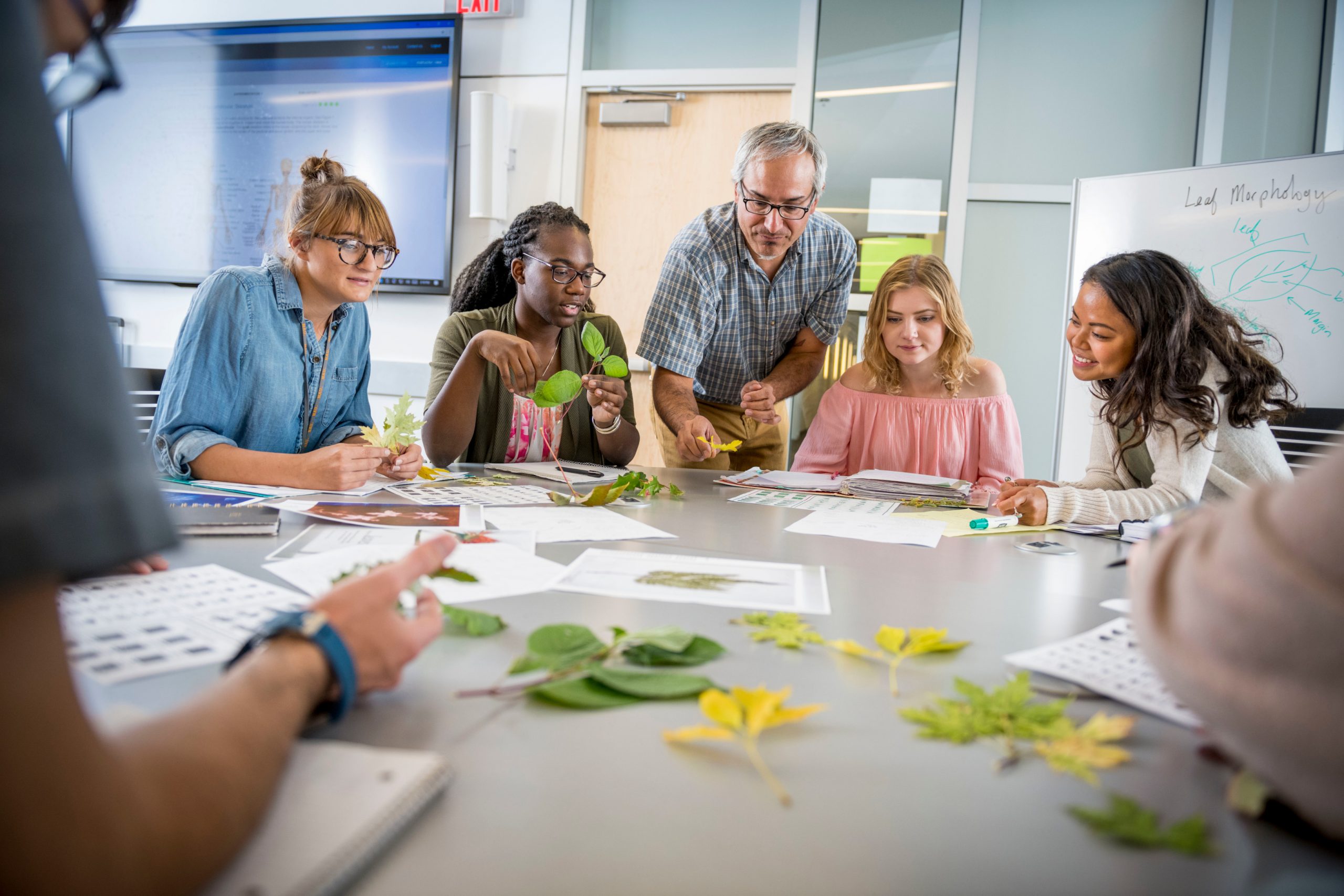 Students gather around table and complete a learning exercise.