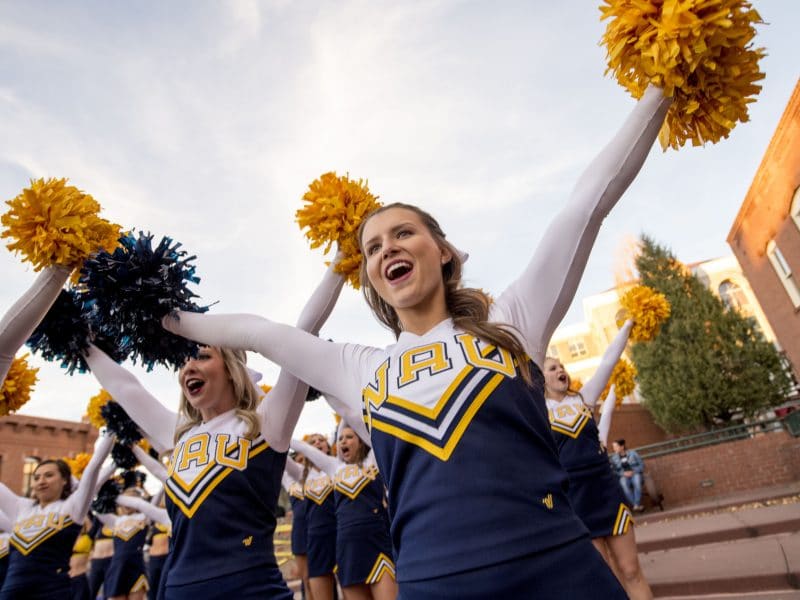 NAU cheerleaders cheer outside.