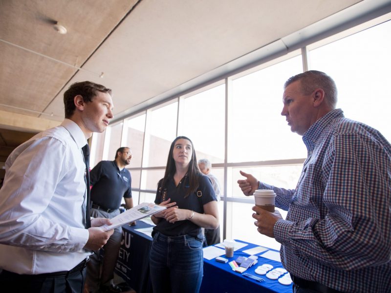 NAU alumni talks with students at career fair.