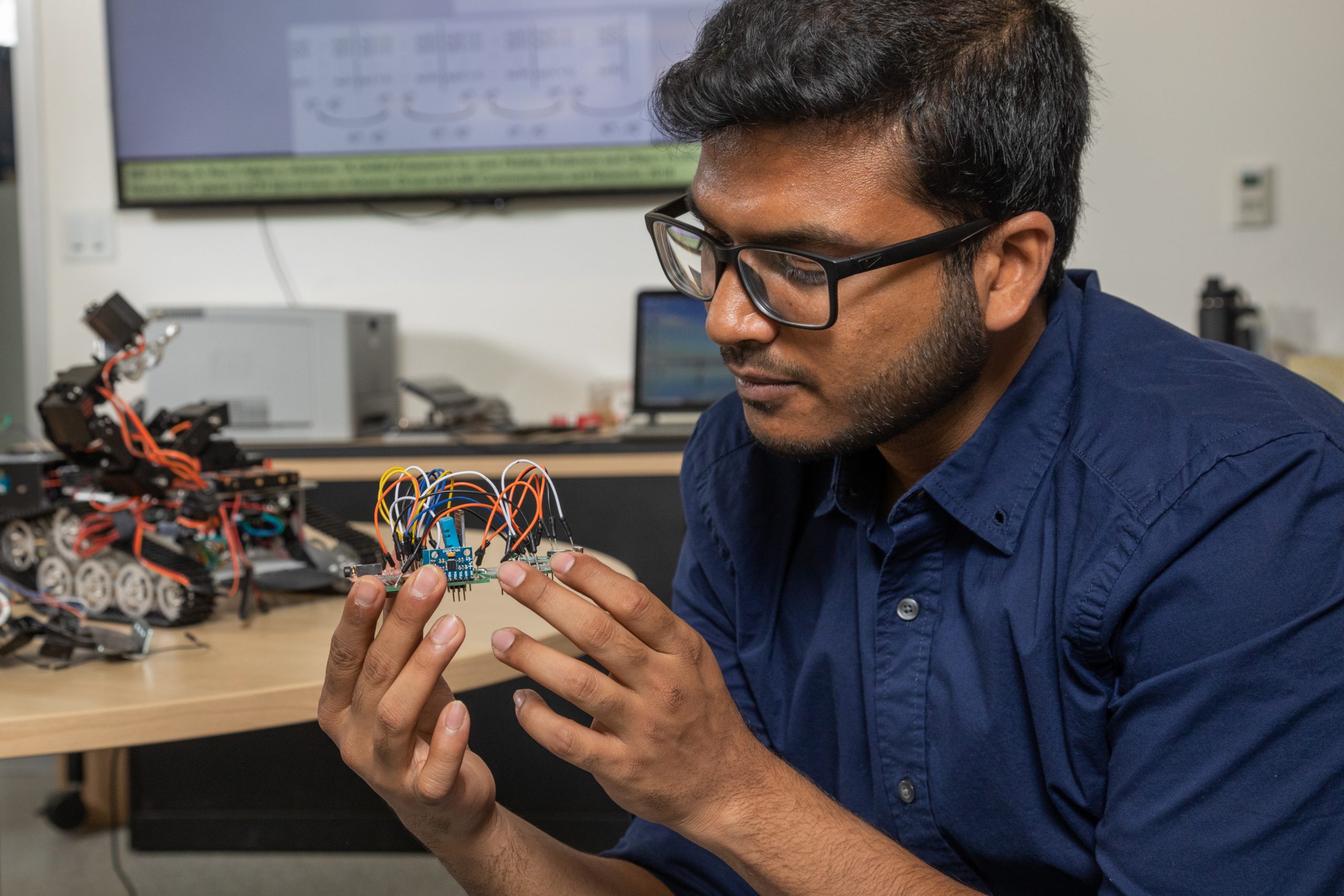 Student proudly observing project in lab.
