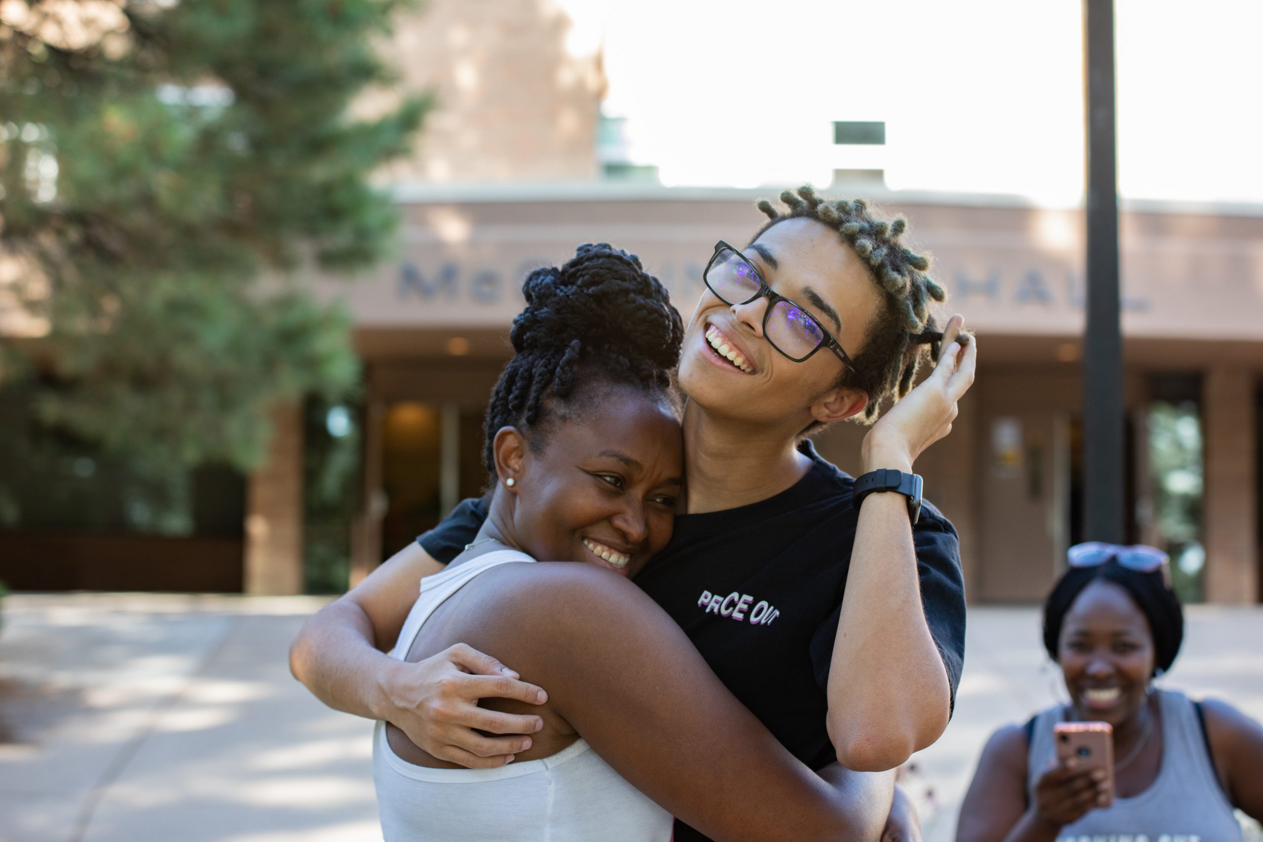 Students hugging while smiling at the camera.