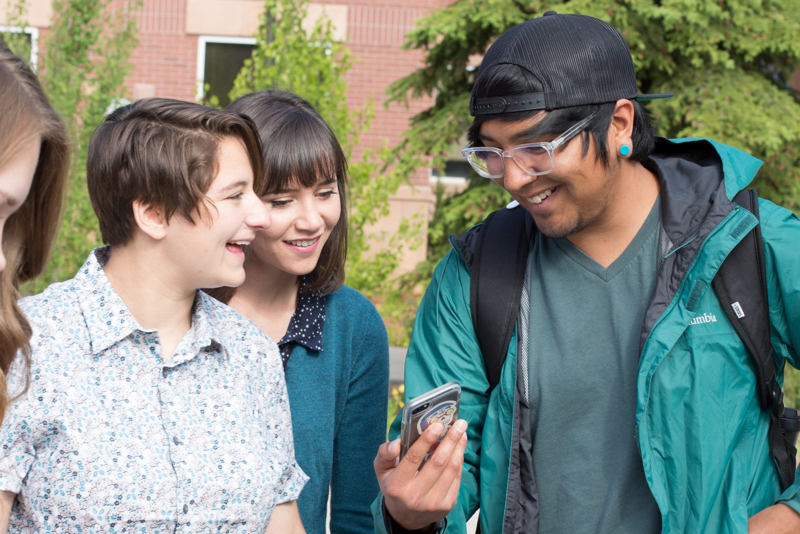 Student shows other students their phone while laughing.