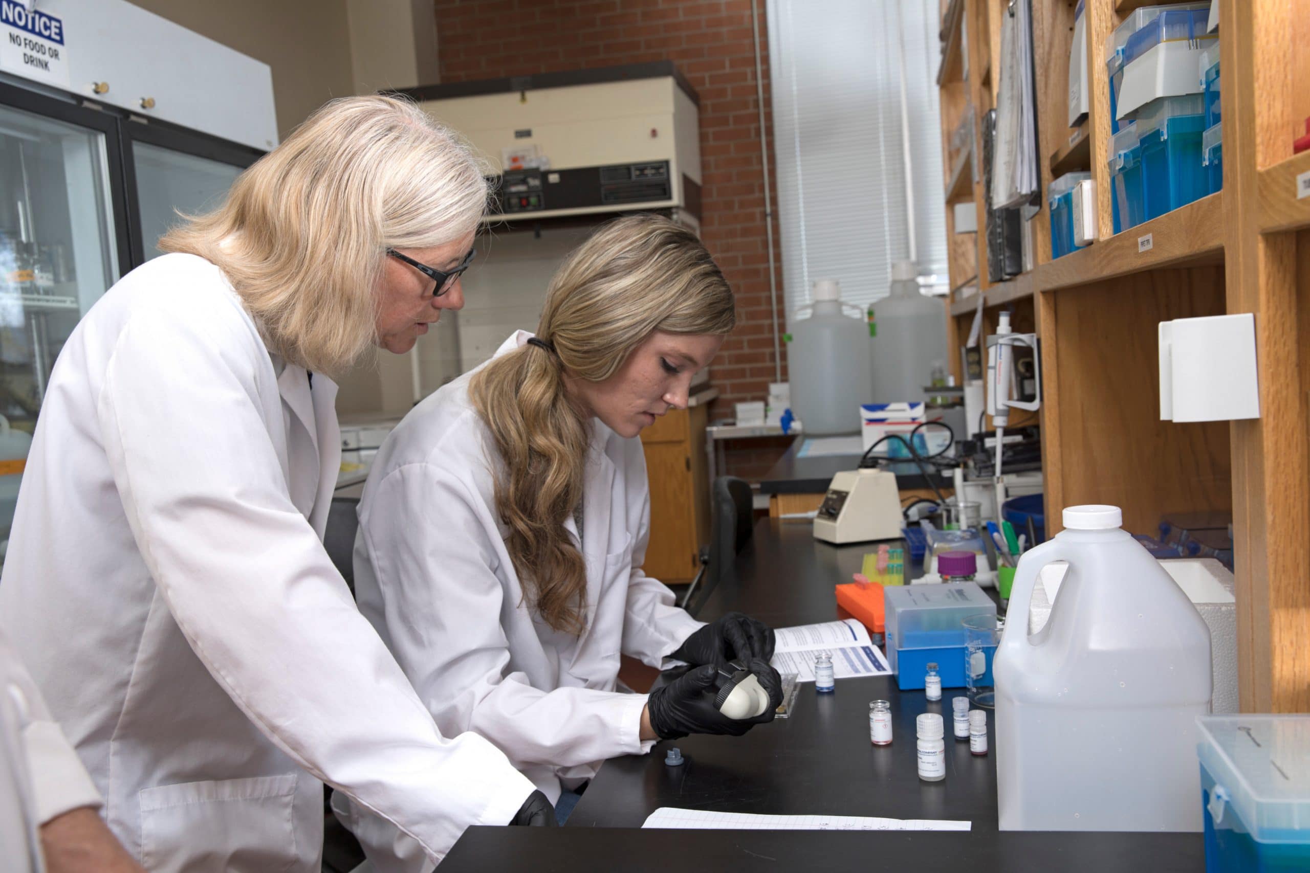 Students wearing lab coats prepare an experiment.