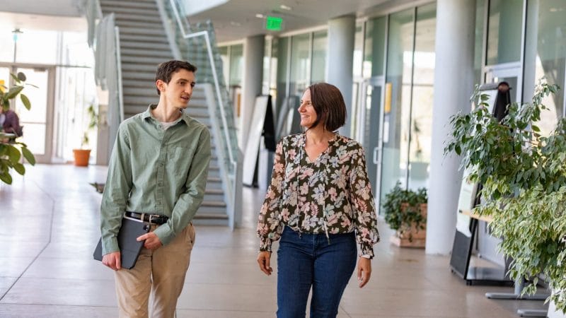 Professor and student walk through building in Flagstaff campus.