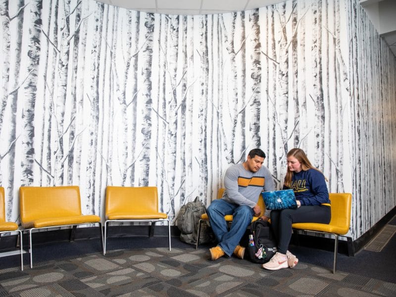 Professor reviewing student's work in a lobby.