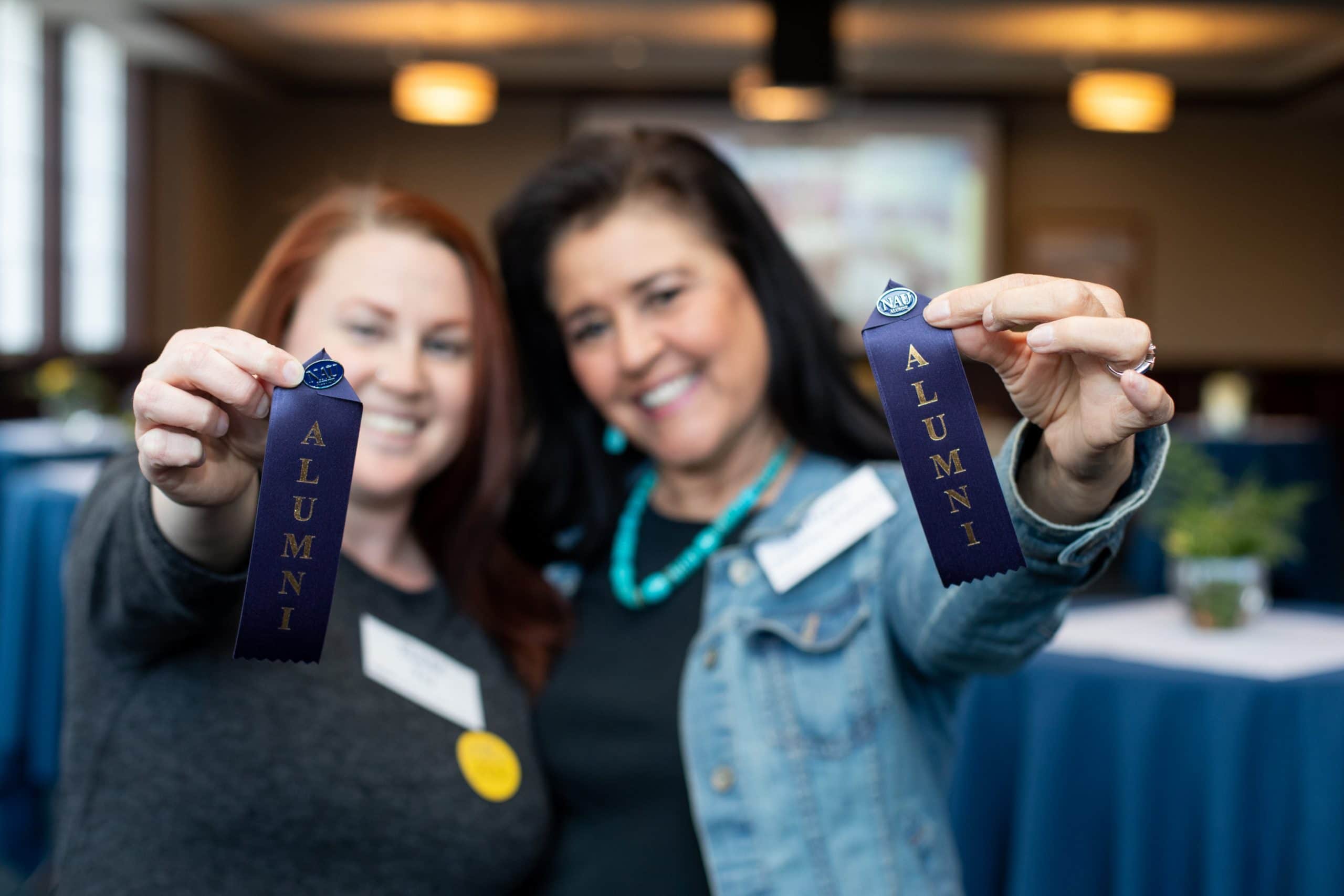 Alumni holding award ribbons.