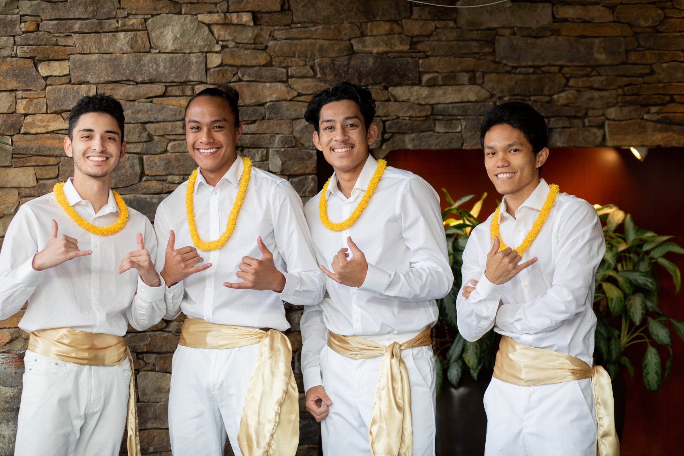 Students wearing leis make "hang loose" signs with their hands.