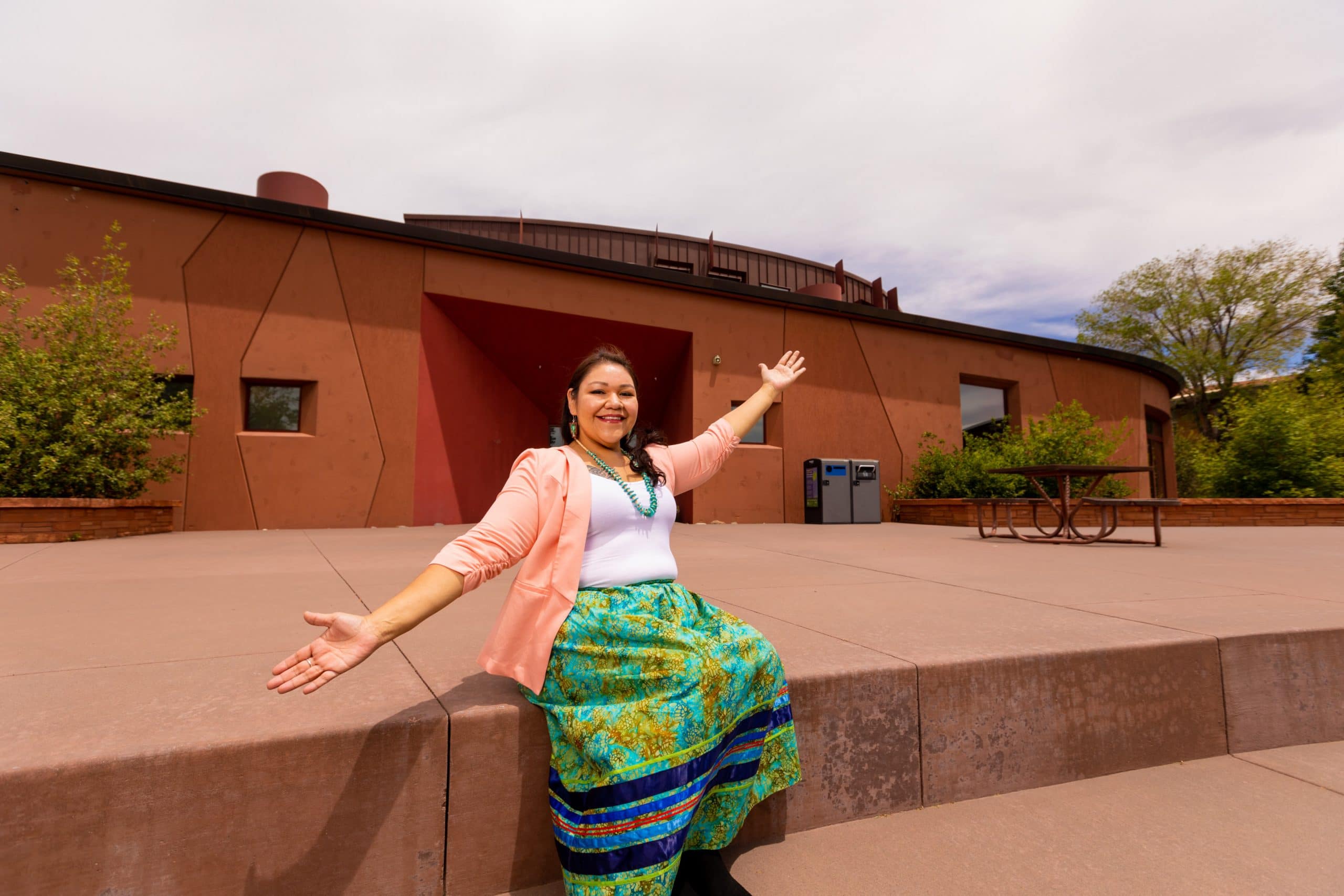 Ora Marek-Martinez sits in front of the N A U Center for Native American and Indigenous Futures (CNAIF).