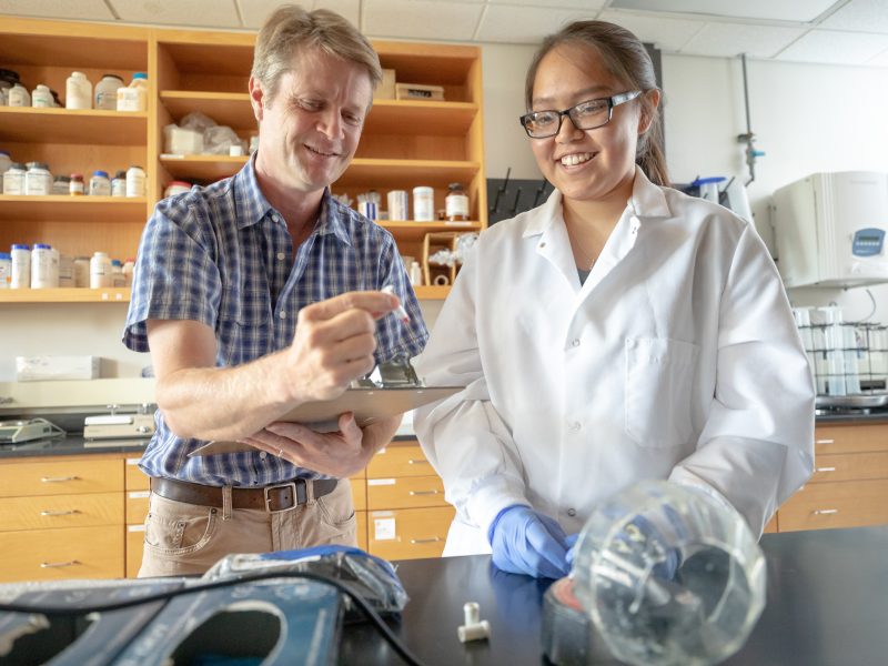 Interim Vice President for Research at N A U, Jason Wilder studies an object in a lab with a student.
