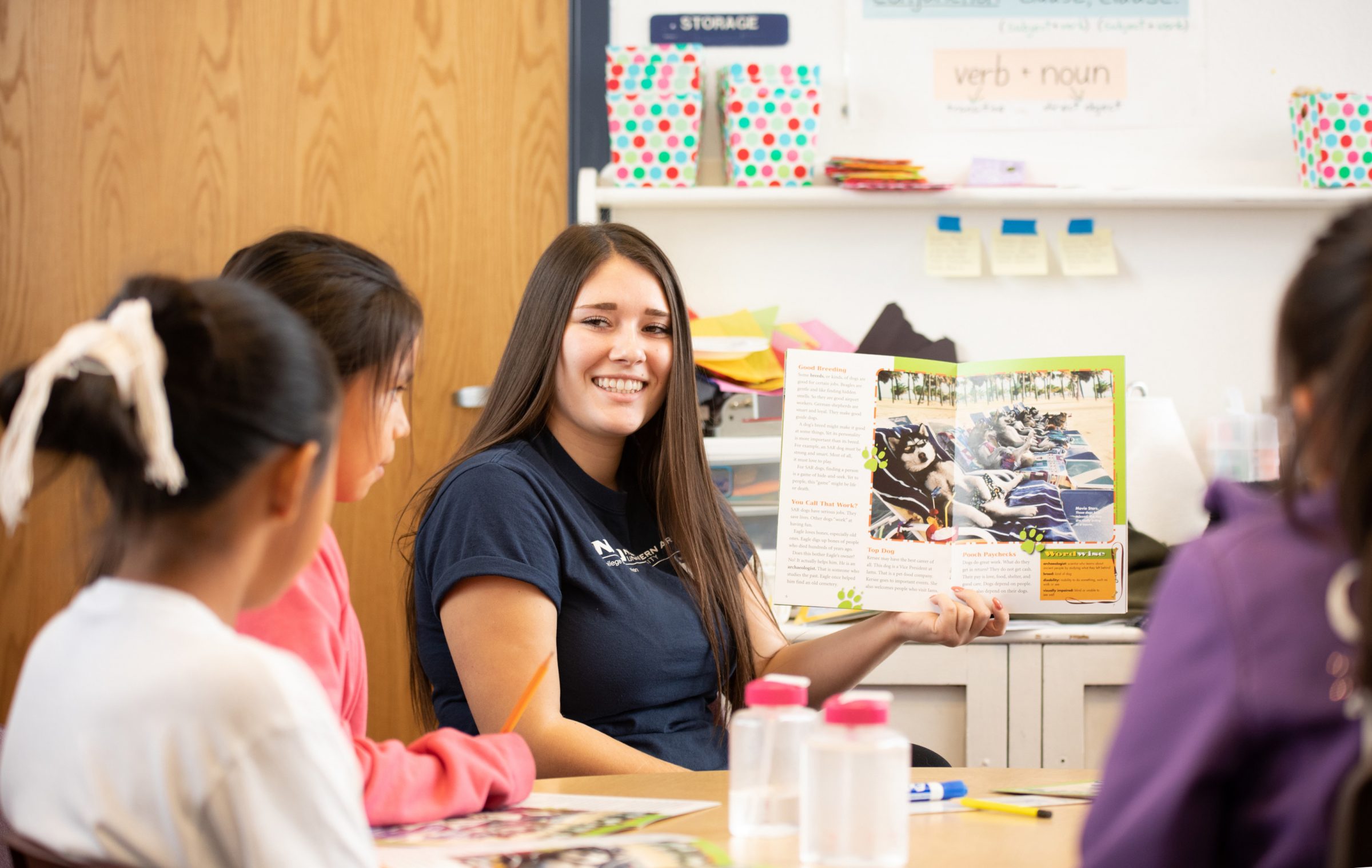 N A U student holding up a information magazine to show elementary students.