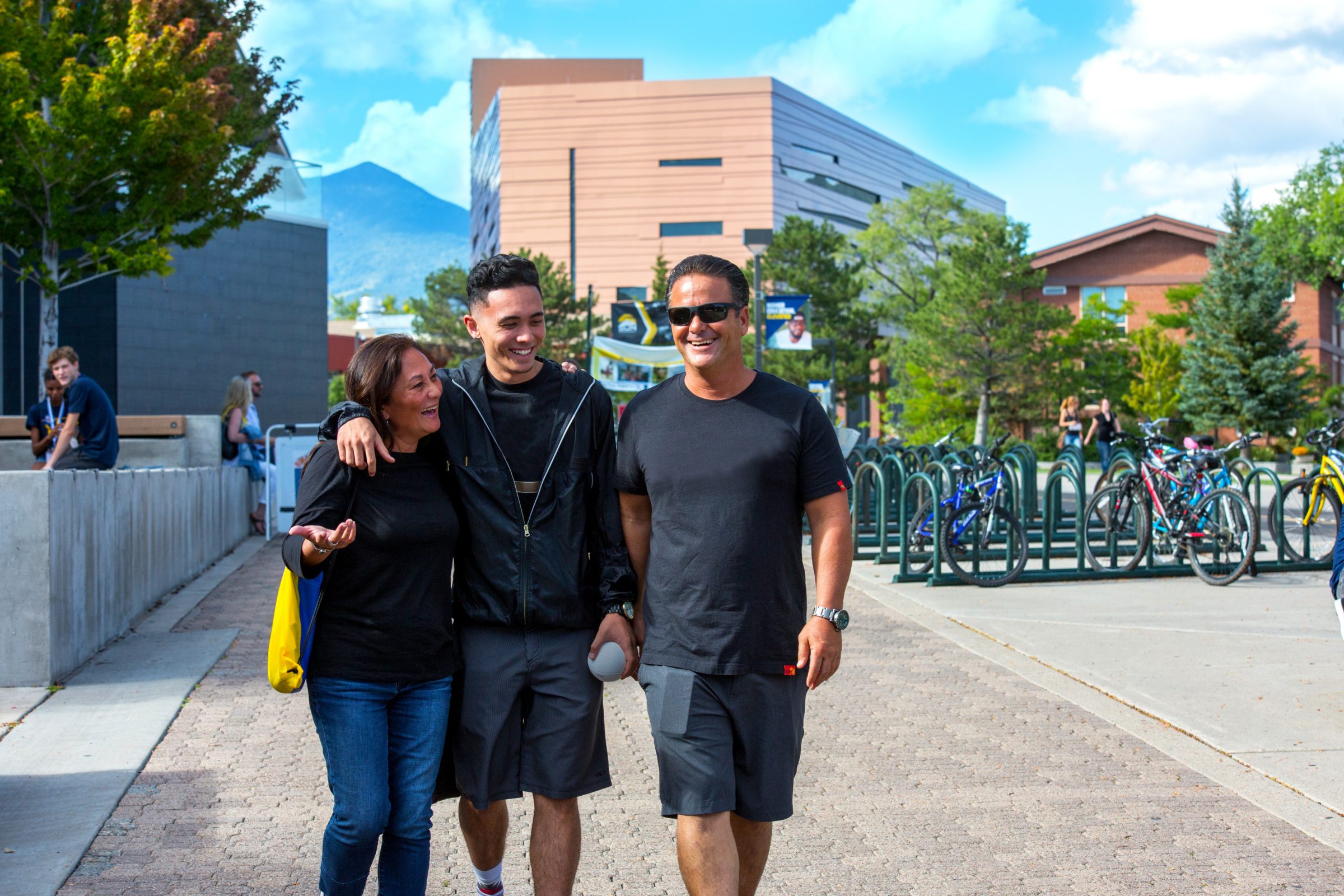 Lumberjack student walks with parents on N A U flagstaff campus.