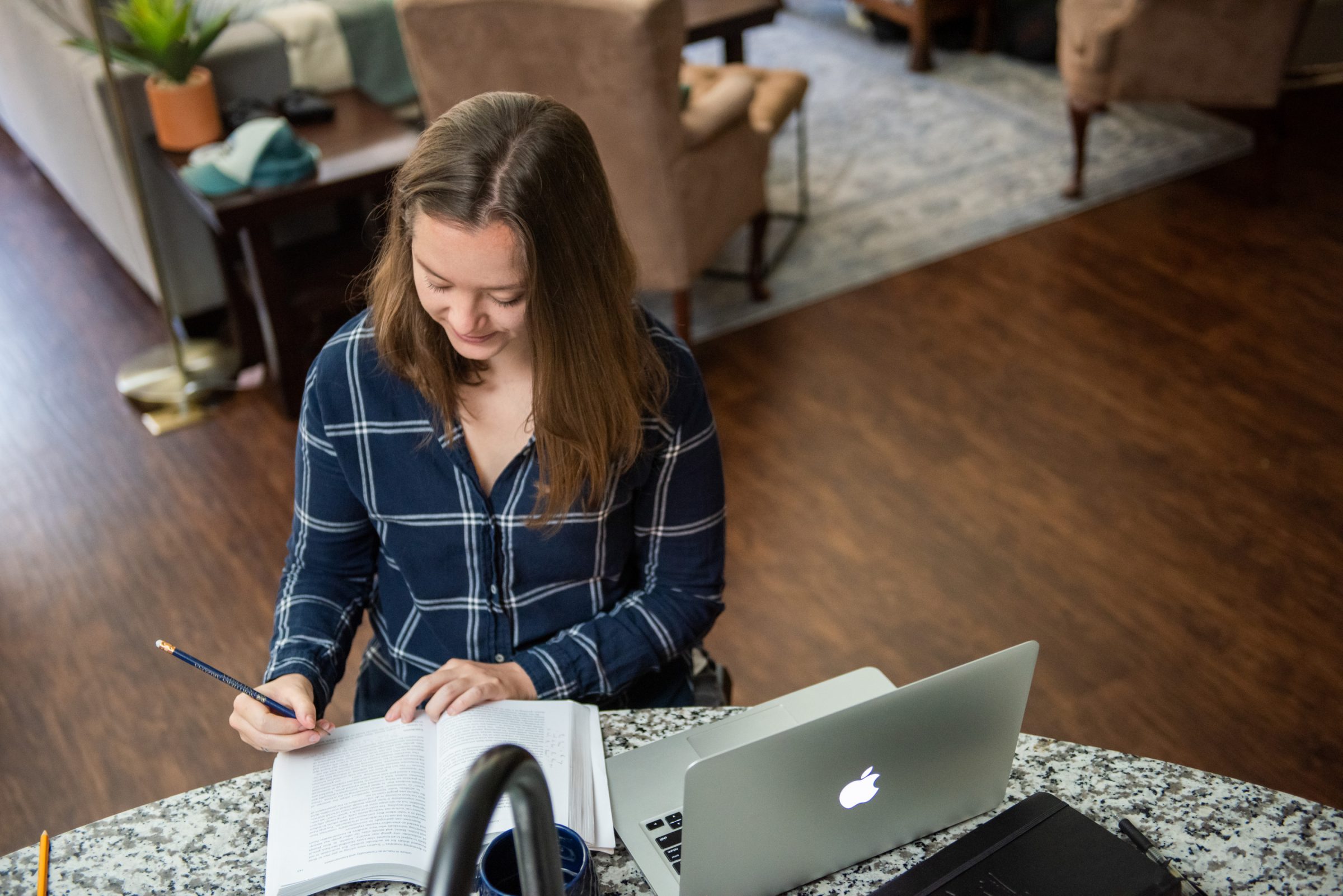 Online student reads textbook while sitting at the kitchen counter.