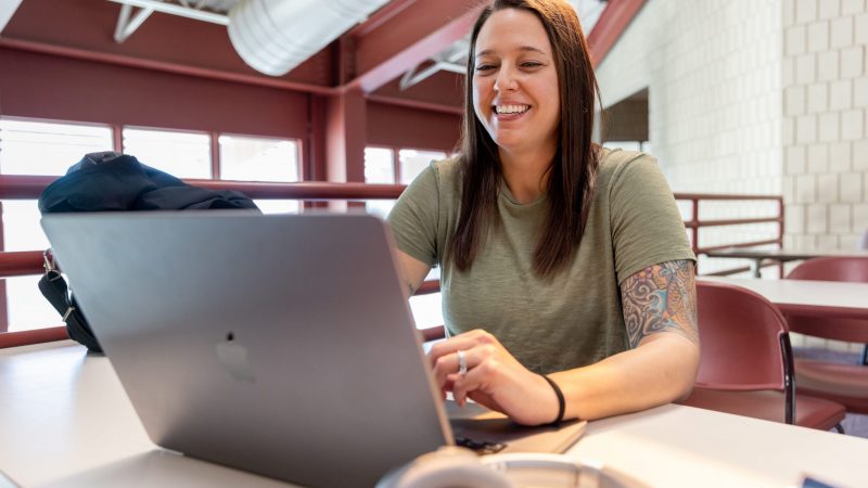 Jessica Stuart smiles while working on their laptop.