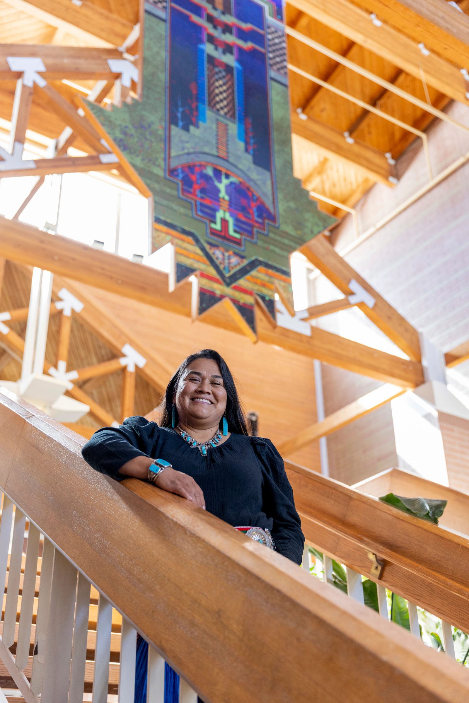 Nikki Cooley stands on a staircase smiling.