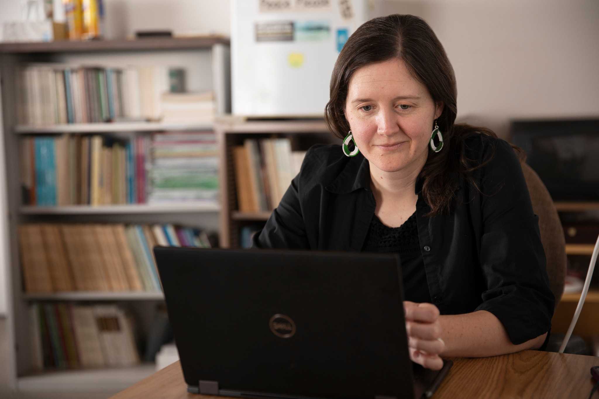 Associate Professor of Anthropology, Emery Eaves, working on their laptop.