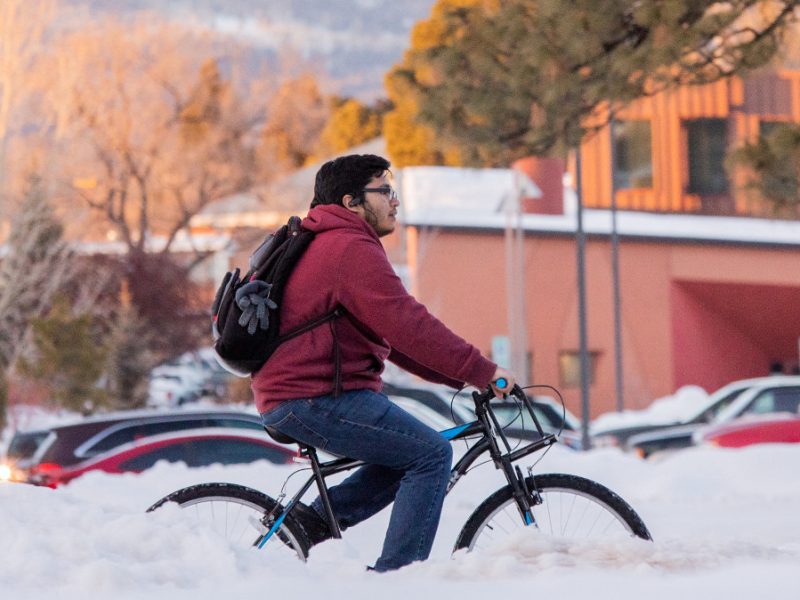 A student riding their bike on the N A U campus is in the winter.