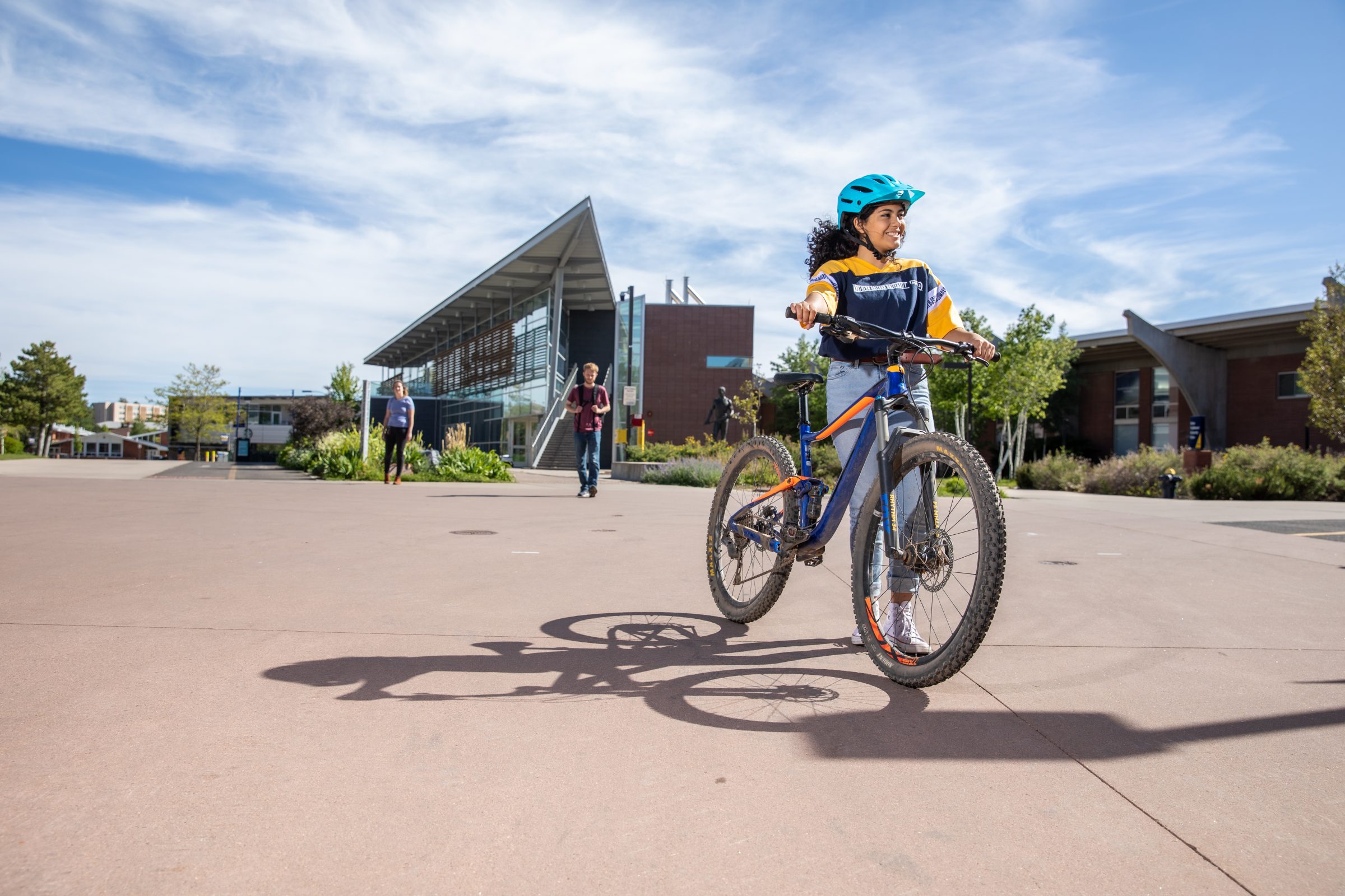 A student walks with their bike at N A U.