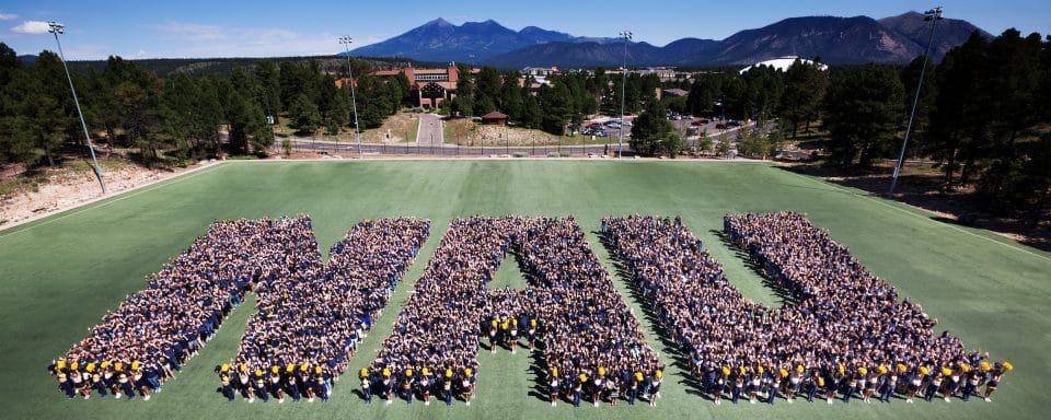 NAU students on the field standing in a formation spelling out NAU