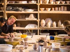Professor helping students through their ceramic-making projects.