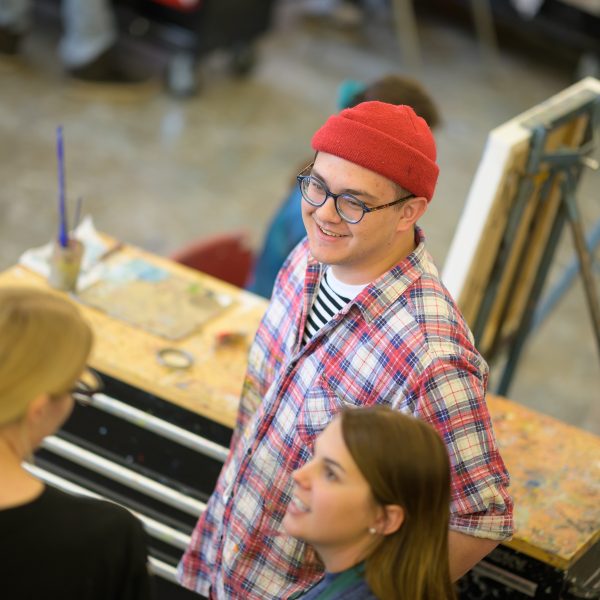 Students gathered around talking in a paint room.