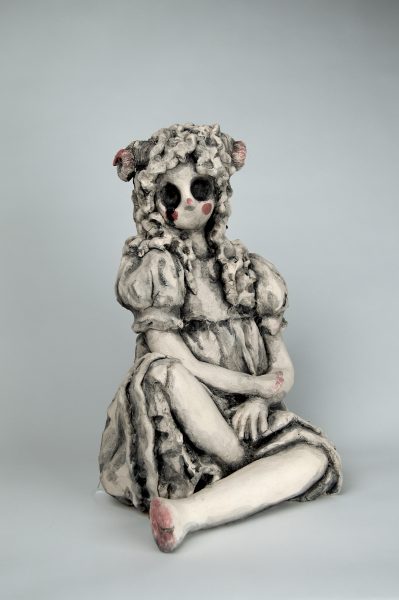 Humanoid sculpture with hollow eyes in a dress.