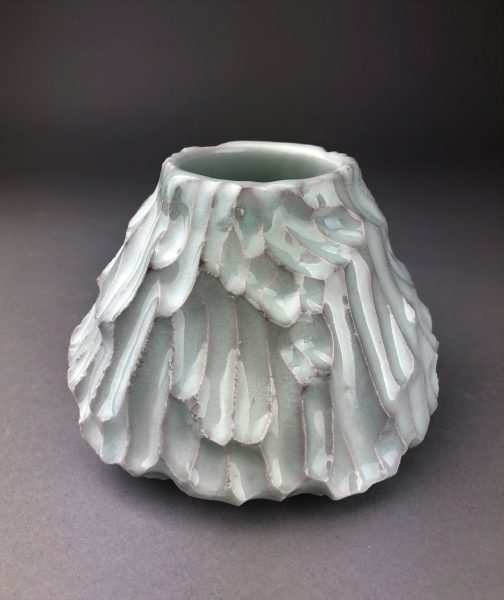 A teal, scaled, ceramic volcano-like sculpture called "Mountain."
