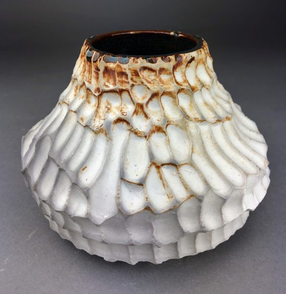A white rustic, ceramic bowl-like sculpture.