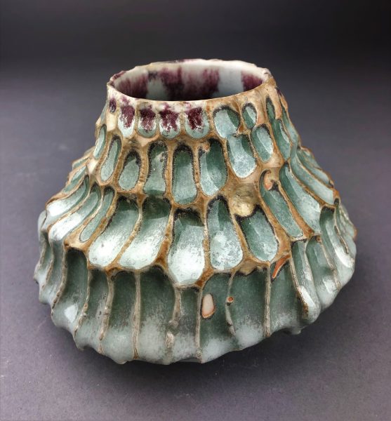 A green and violet ceramic bowl-like sculpture.