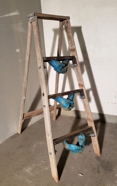 A ladder with blue hand sculptures attached to the bottom of the rungs.