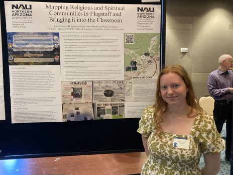 student smiles in front of a poster