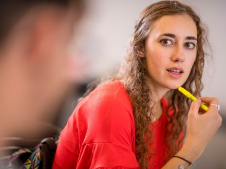 Girl looking at person with pen in her hand