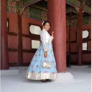 Student in a dress posing against a building