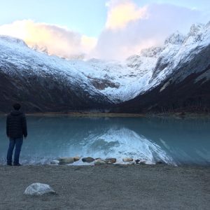 A snowy mountain with water at its base.