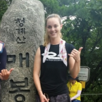 NAU student posing in front of a rock with writing on it.