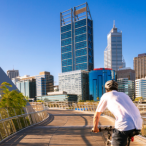 man on bike riding towards tall business building
