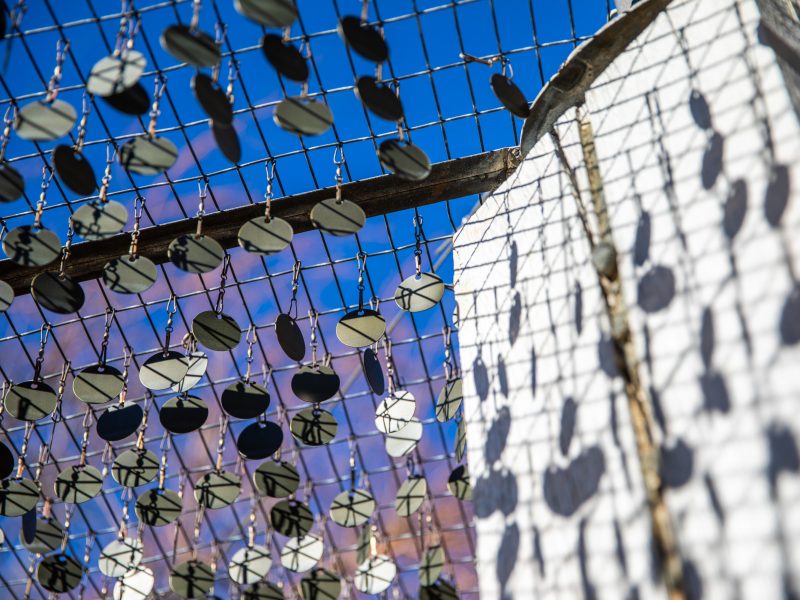 Several silver tags hang from a sculpture on campus.